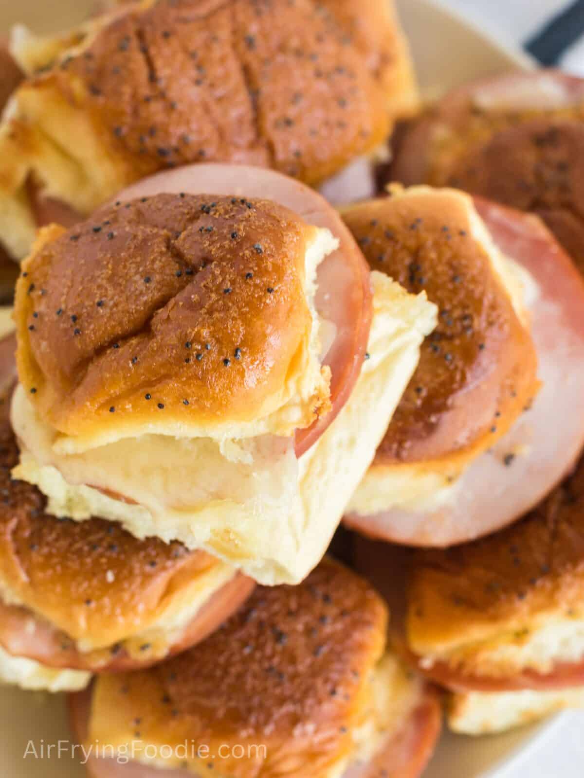 Close up of ham and cheese sliders stacked on a plate and ready to serve. 