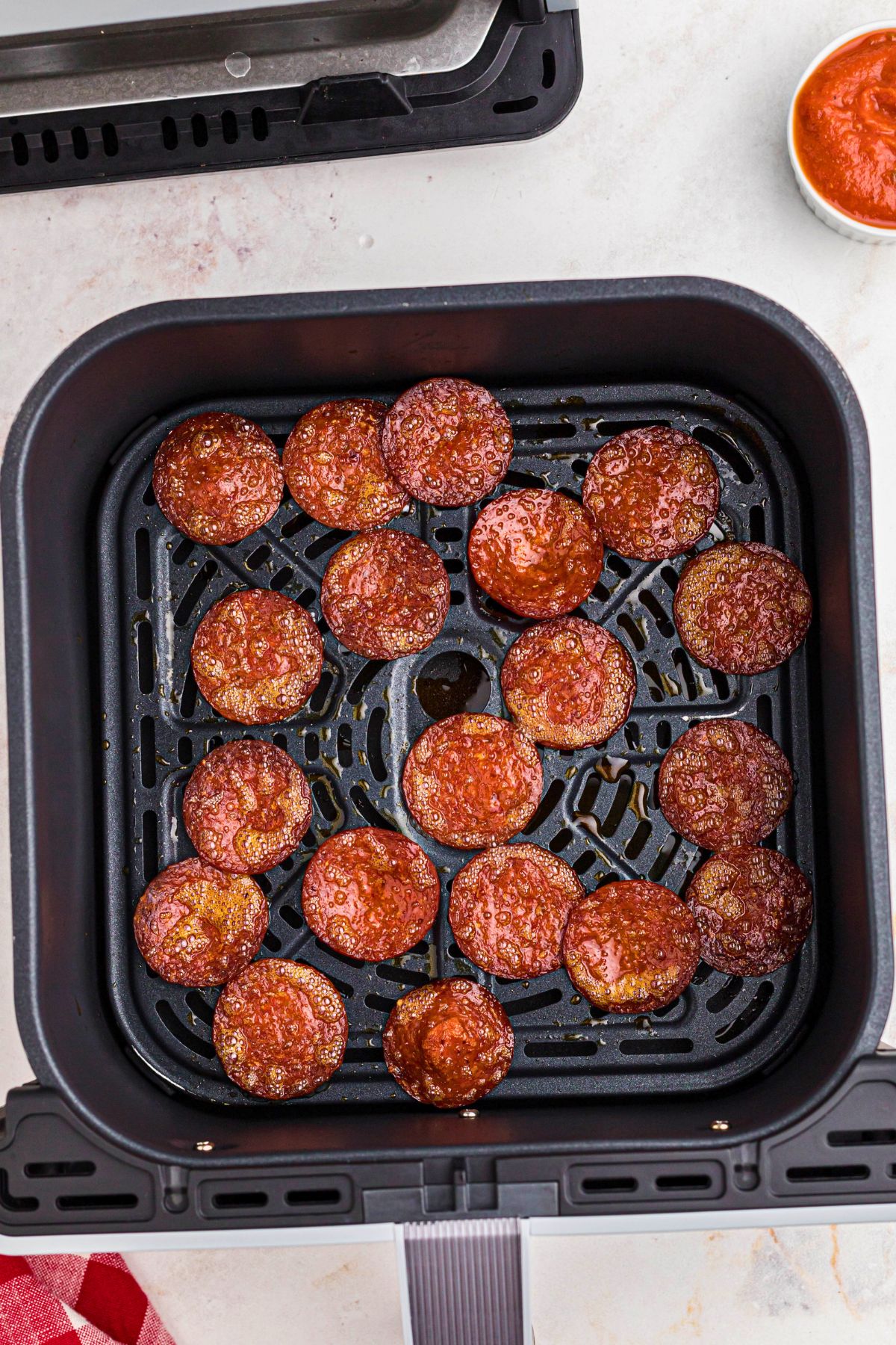 Crispy pepperoni slices air fried in the air fryer basket. 