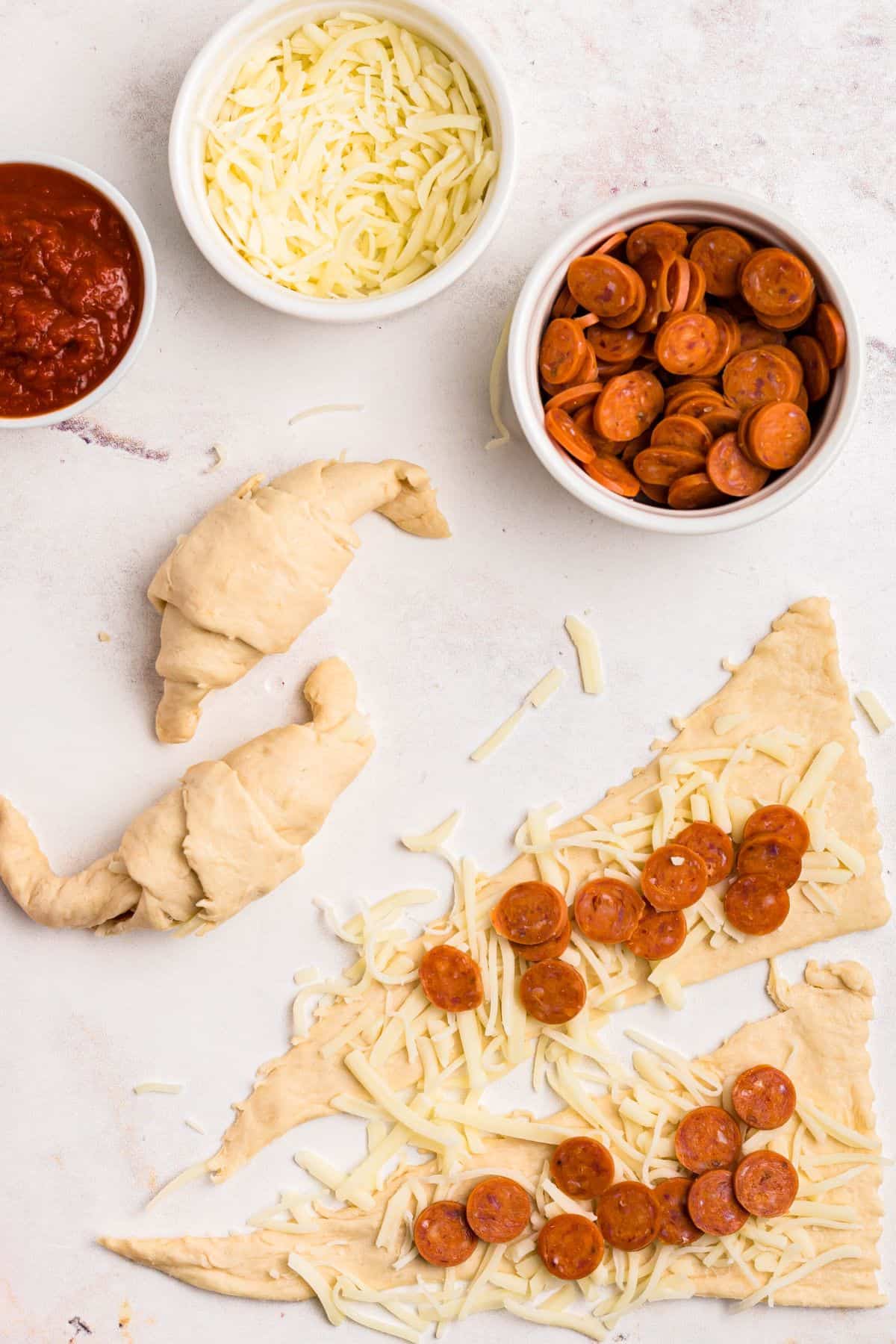 Rolled our crescent rolls with shredded cheese and mini pepperoni on top, with some rolled into crescents. 