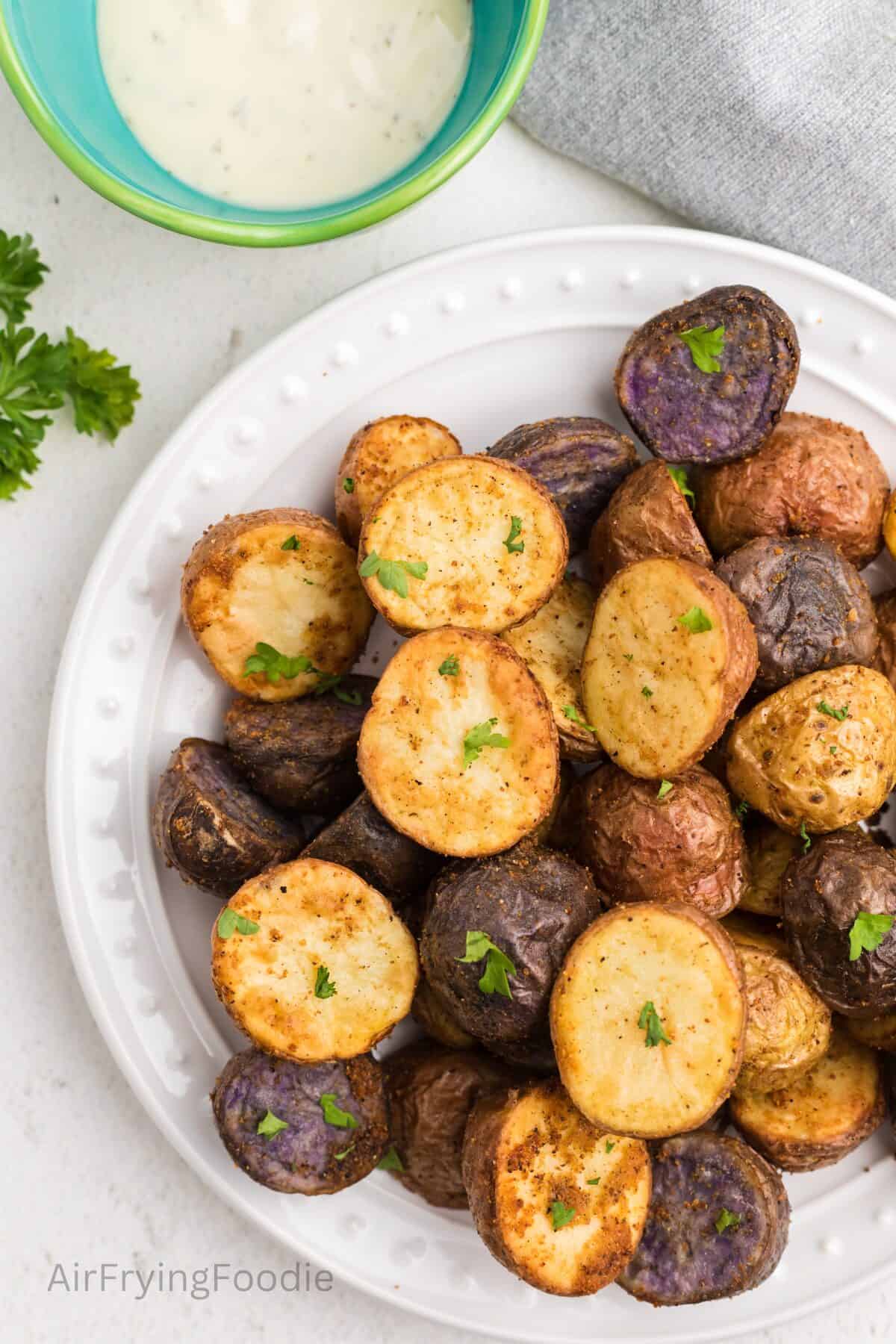 Crispy, roasted potatoes, made in the air fryer, on a white plate ready to eat. 