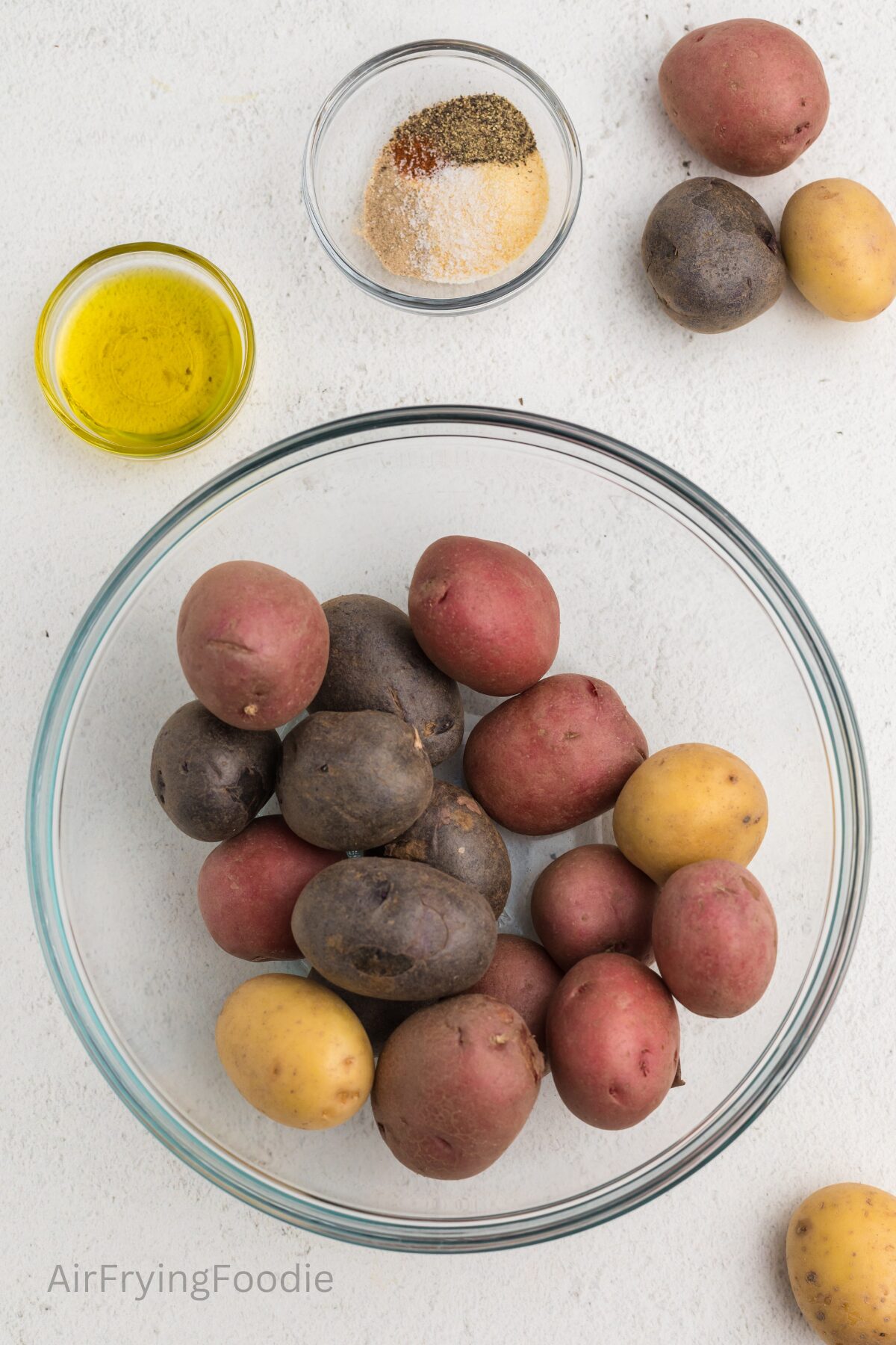 Ingredients on a white tabletop used to make roasted potatoes in the air fryer. 