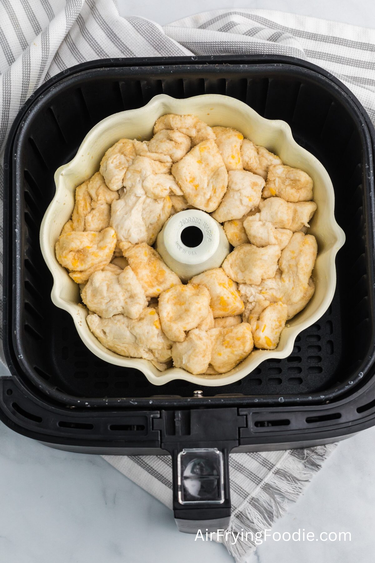 biscuit dough and sugar placed in a bundt pan in the basket of the air fryer. 