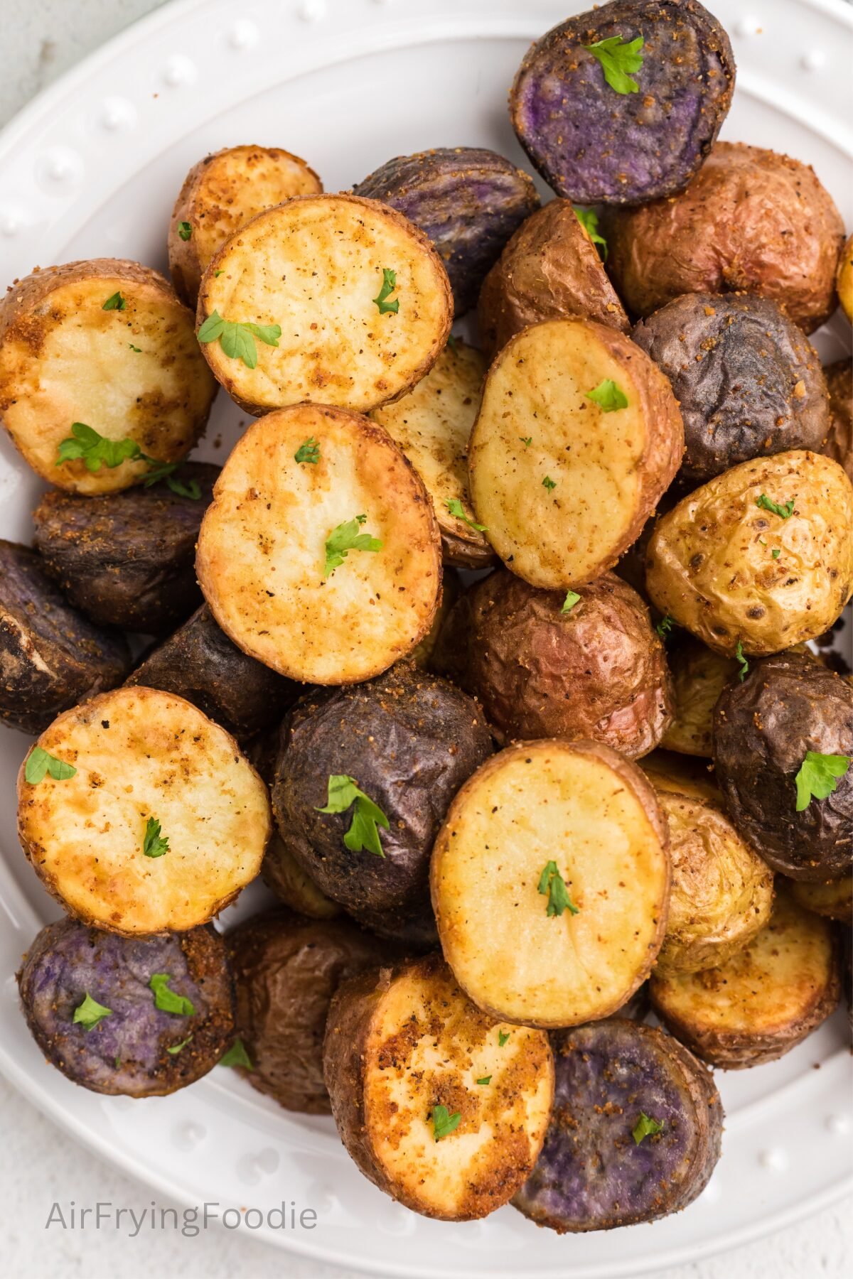 Crispy air fryer roasted potatoes, seasoned and served on a white plate. 