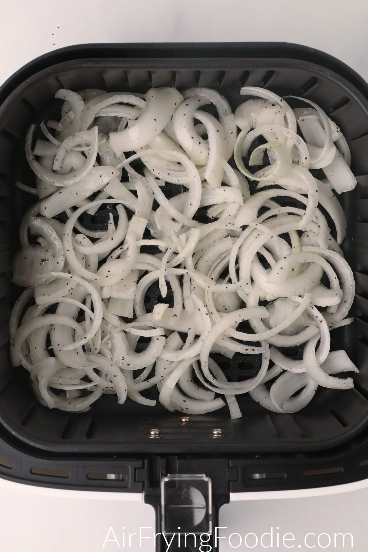 Onions in the basket of the air fryer, ready to cook. 