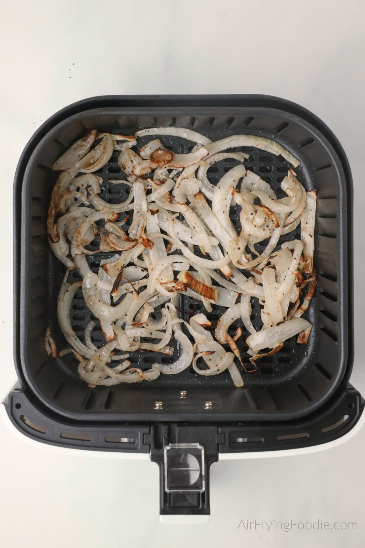 Crispy air fried onions in the basket of the air fryer. 