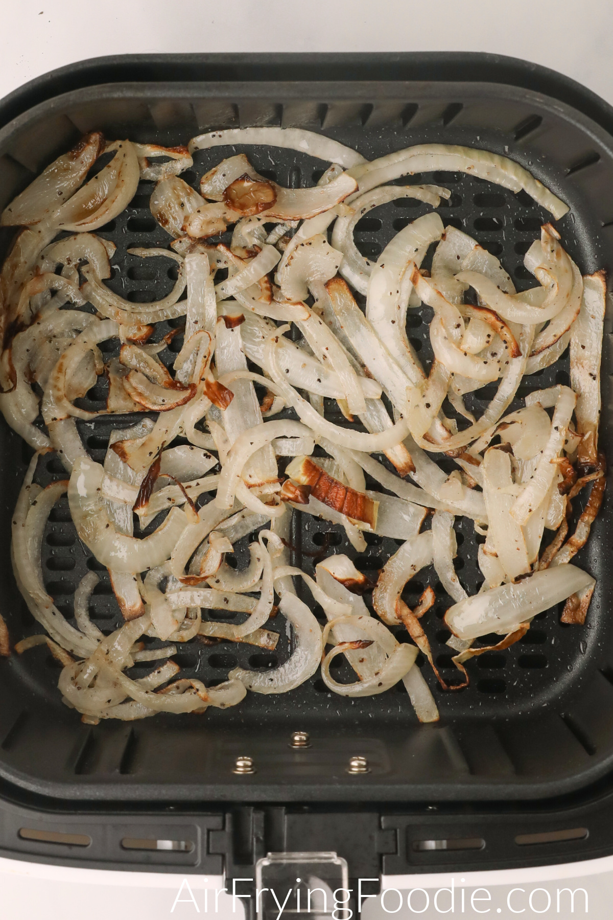 Crispy cooked air fryer onions in the basket of the air fryer, ready to serve.