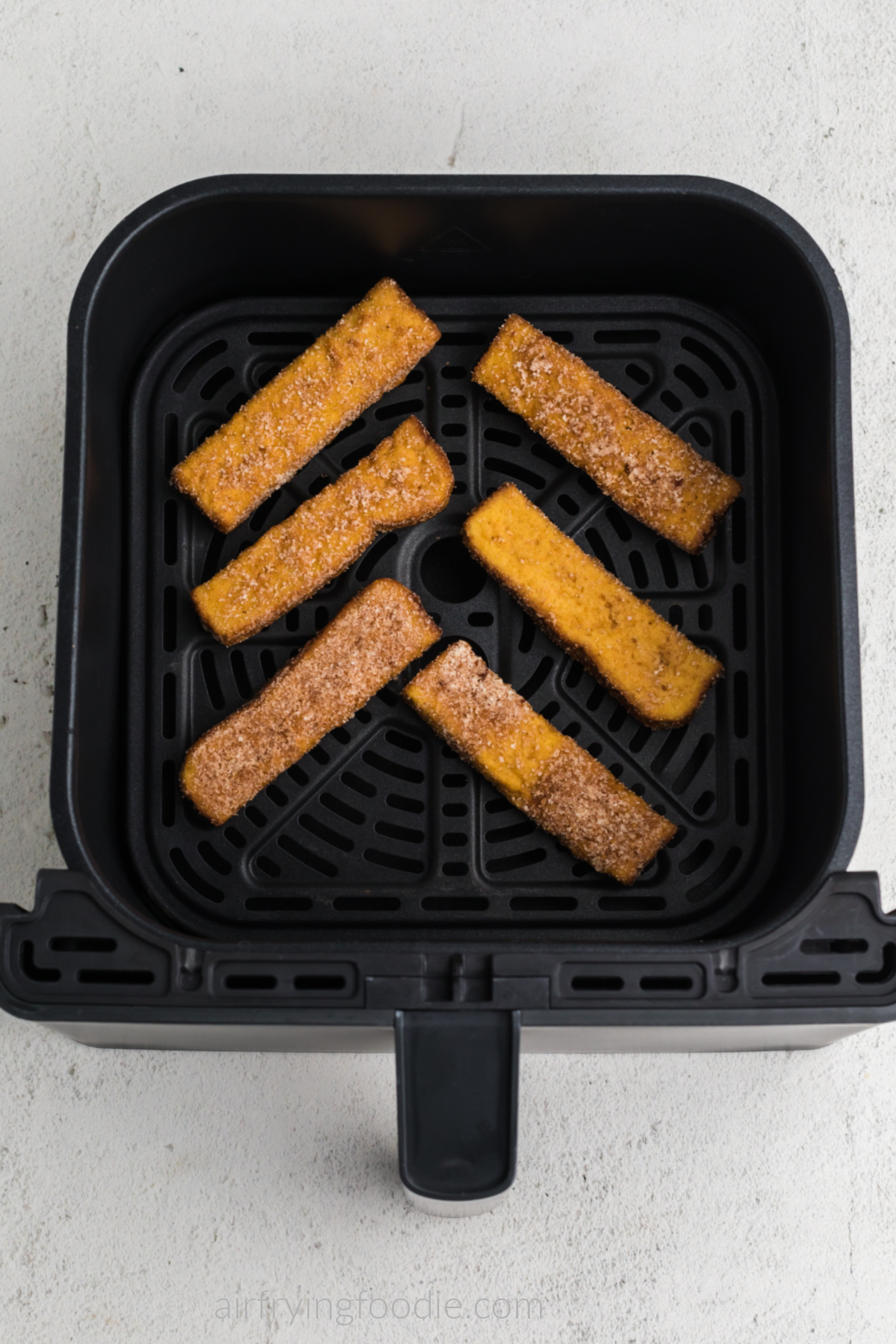 Frozen french toast sticks in air fryer basket in a single layer. Ready to cook. 