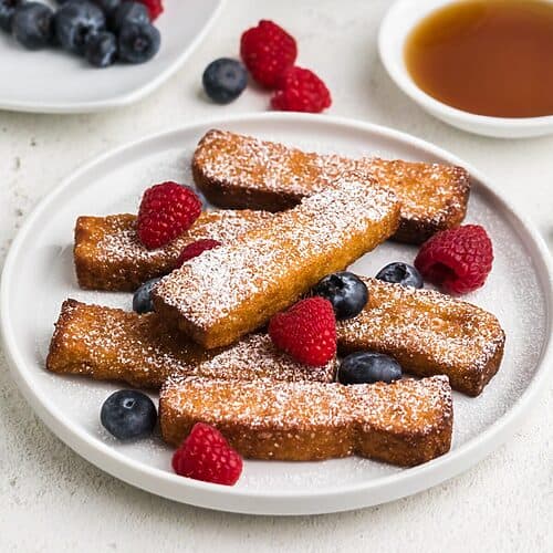 Air fried frozen french toast sticks fully cooked and topped with berries and powdered sugar. Ready to eat.