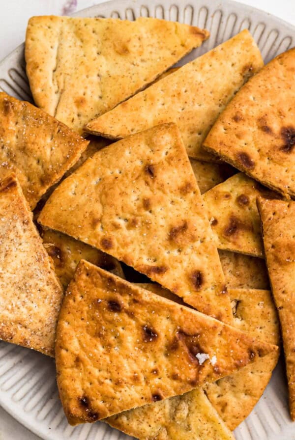 Crispy golden chips on a white plate in front of an air fryer.