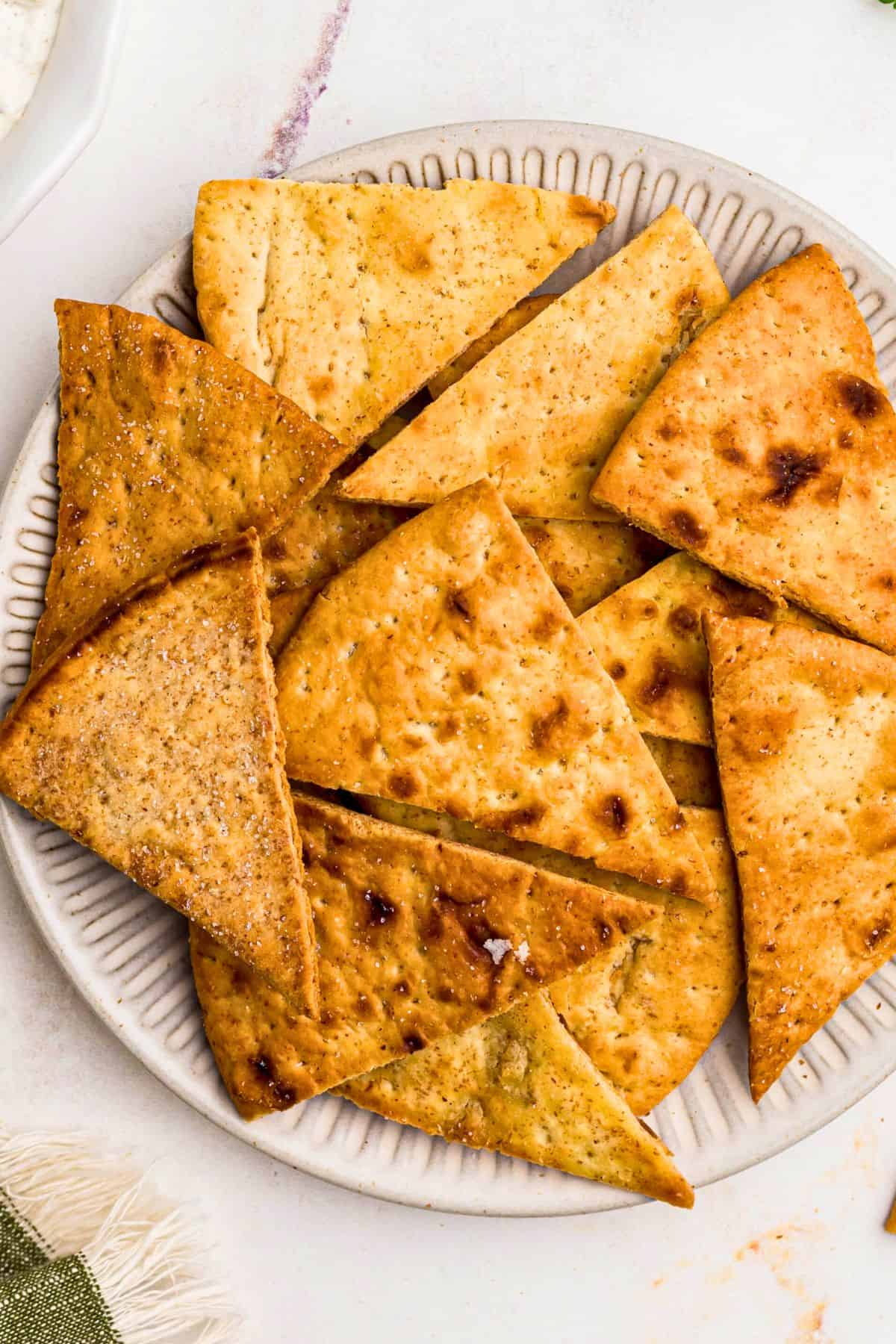 Crispy golden chips on a white plate in front of an air fryer.