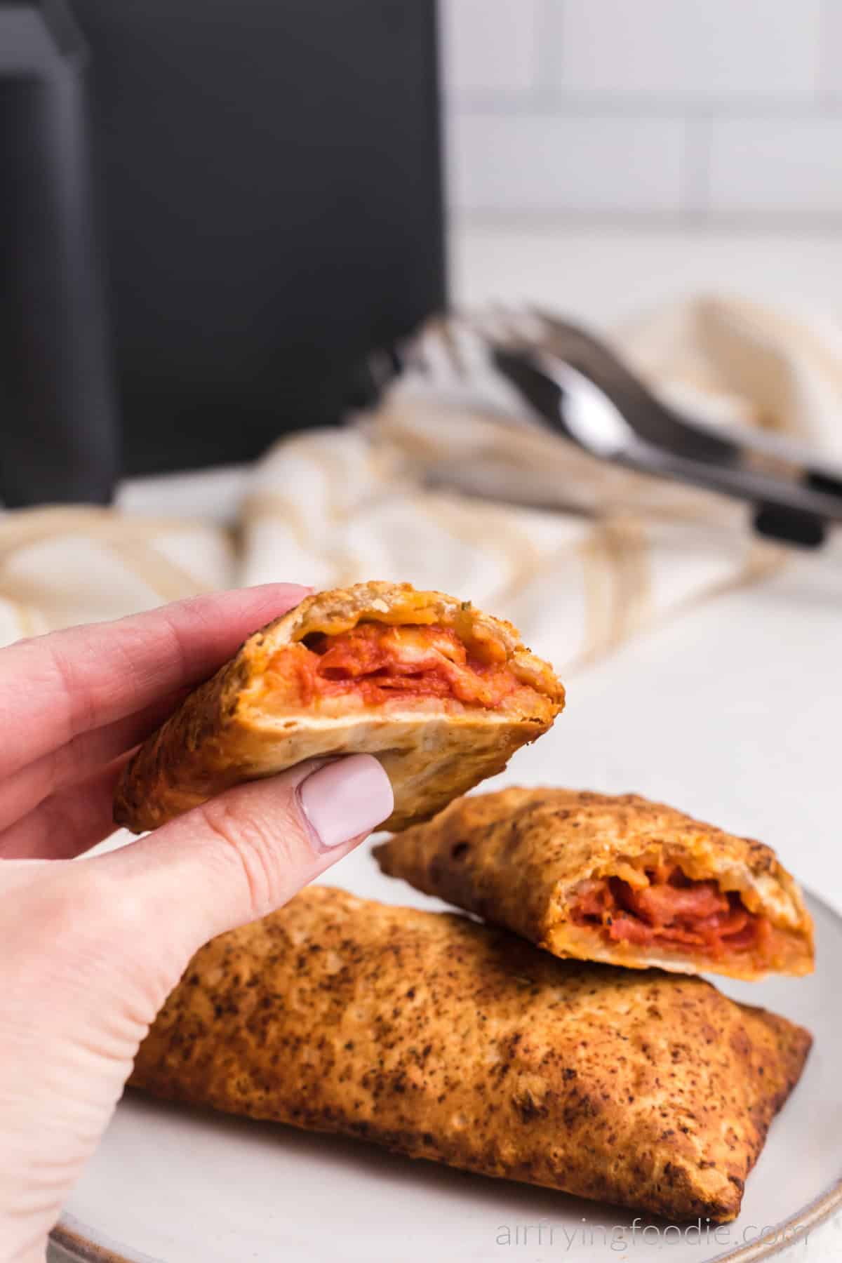 Hand holding a half of an air fried  hot pocket, ready to eat. 