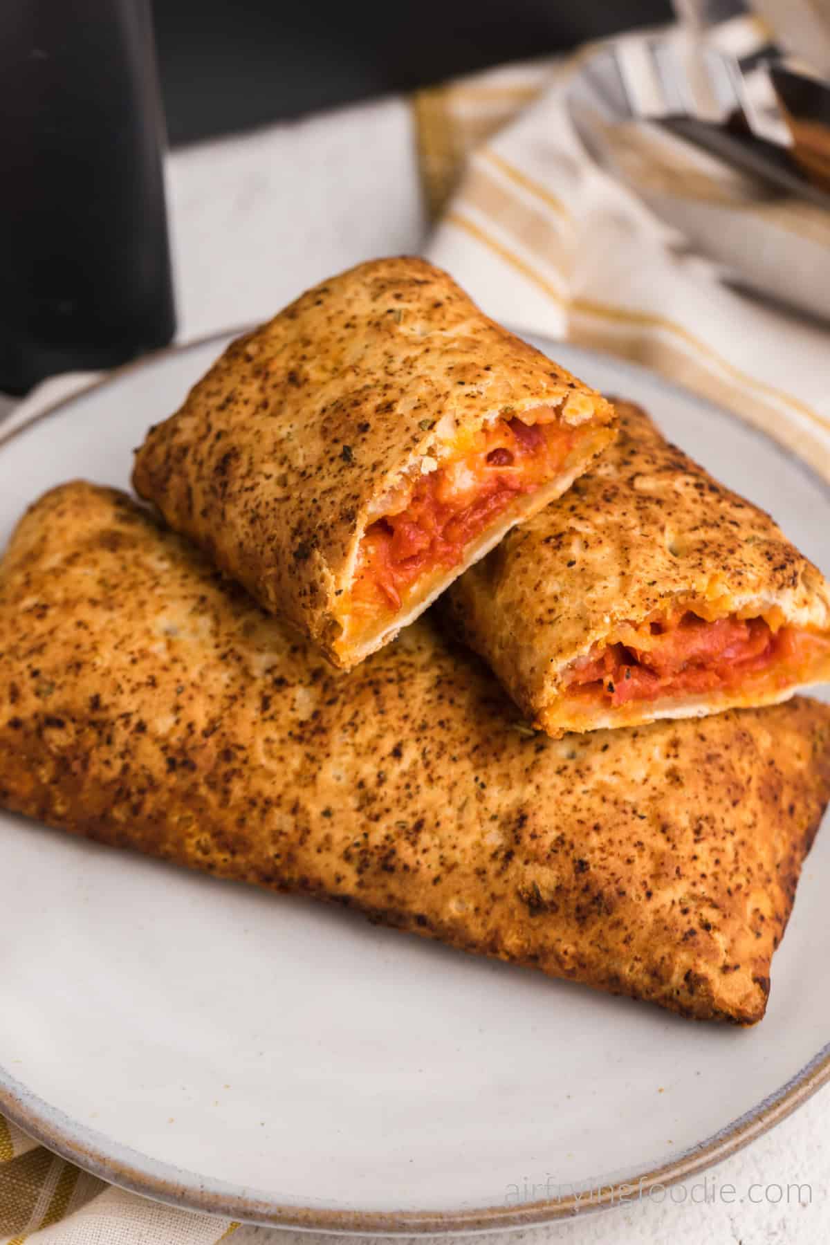 Air fried hot pockets on a plate with one cut in half. 