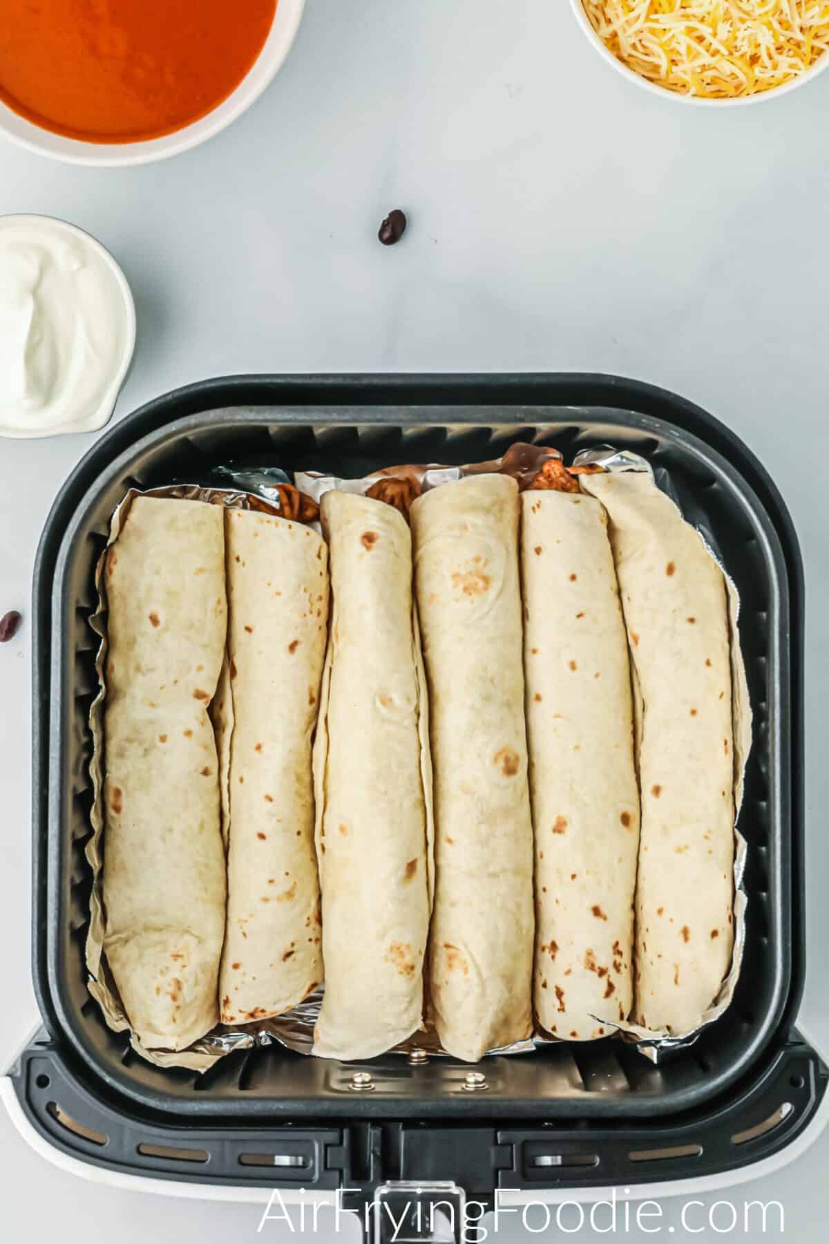 Enchiladas rolled and placed into the air fryer basket. 