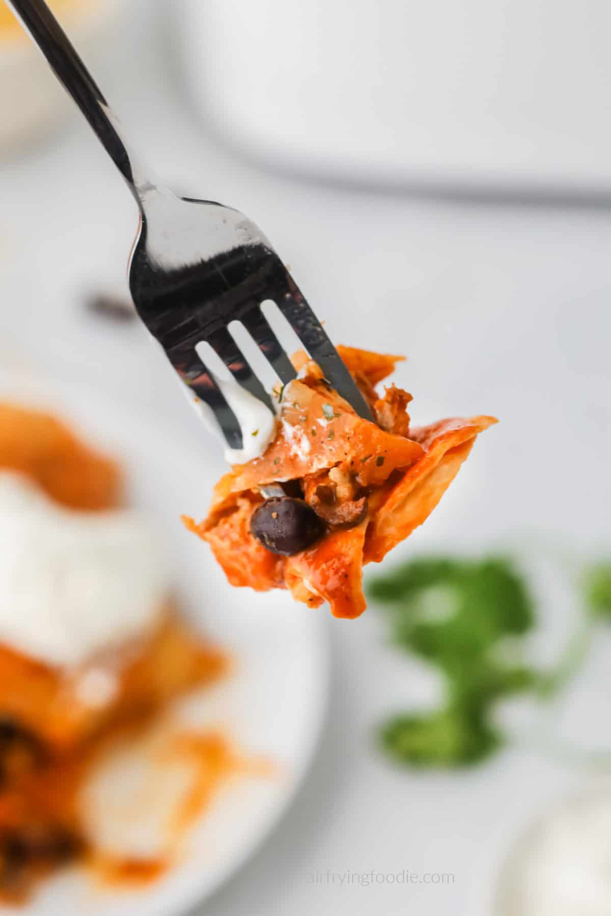 Bite of air fried chicken enchiladas on a fork. 