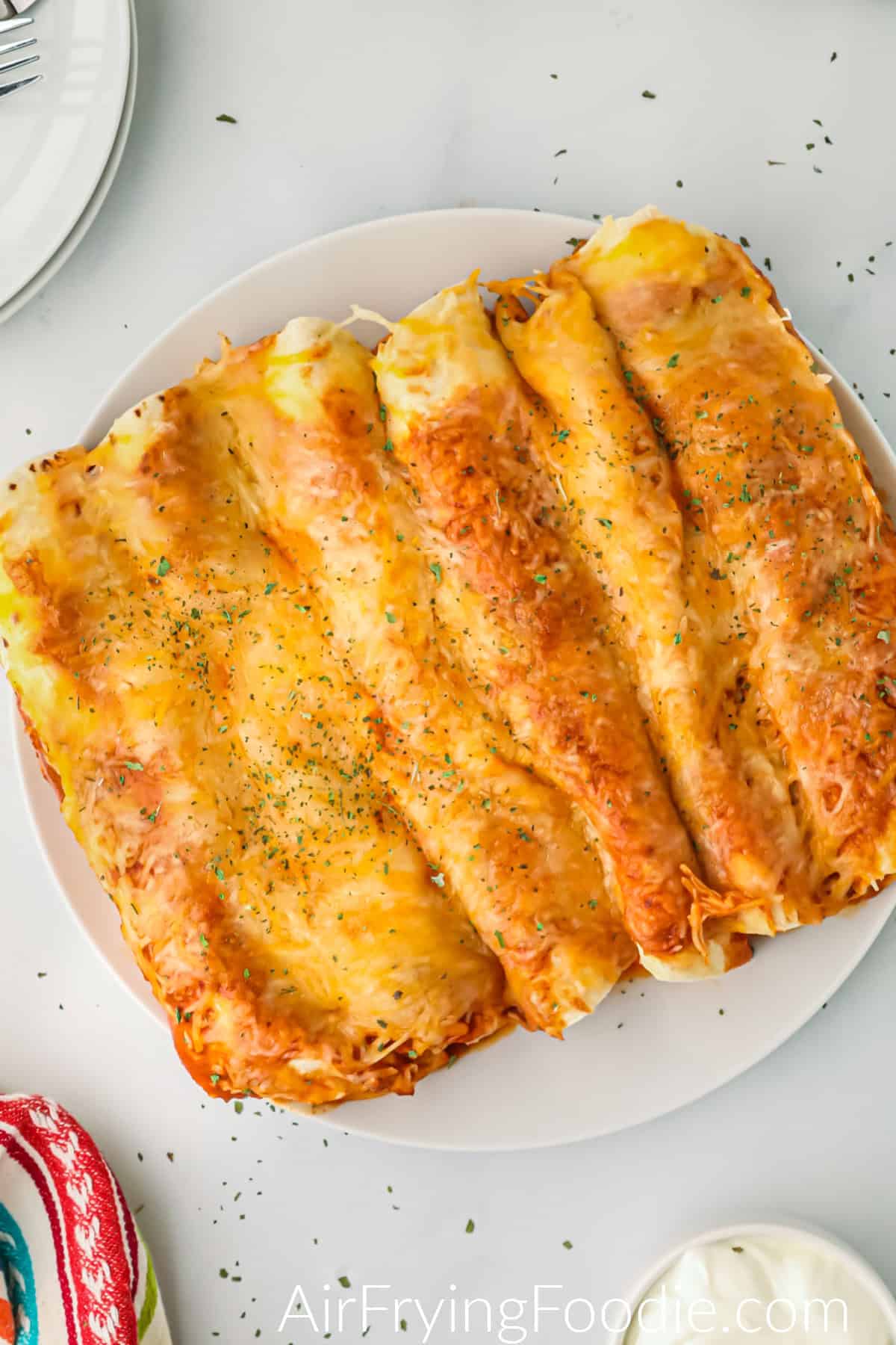 Enchiladas made in the air fryer, served on a white plate and ready to eat. 