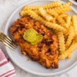 Air fryer Nashville Hot Chicken on a white plate with French fries as a side.