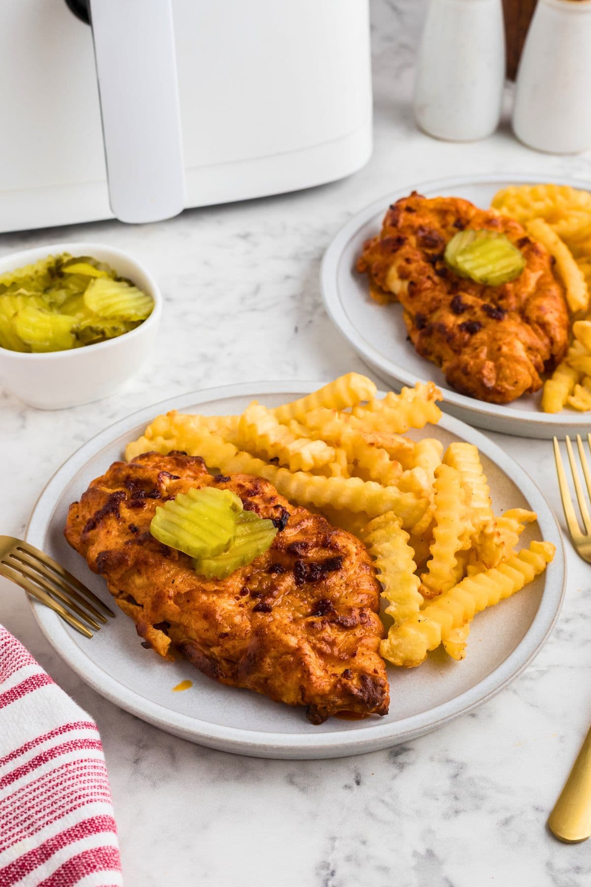 Air fryer Nashville Hot Chicken on a white plate with French fries as a side.
