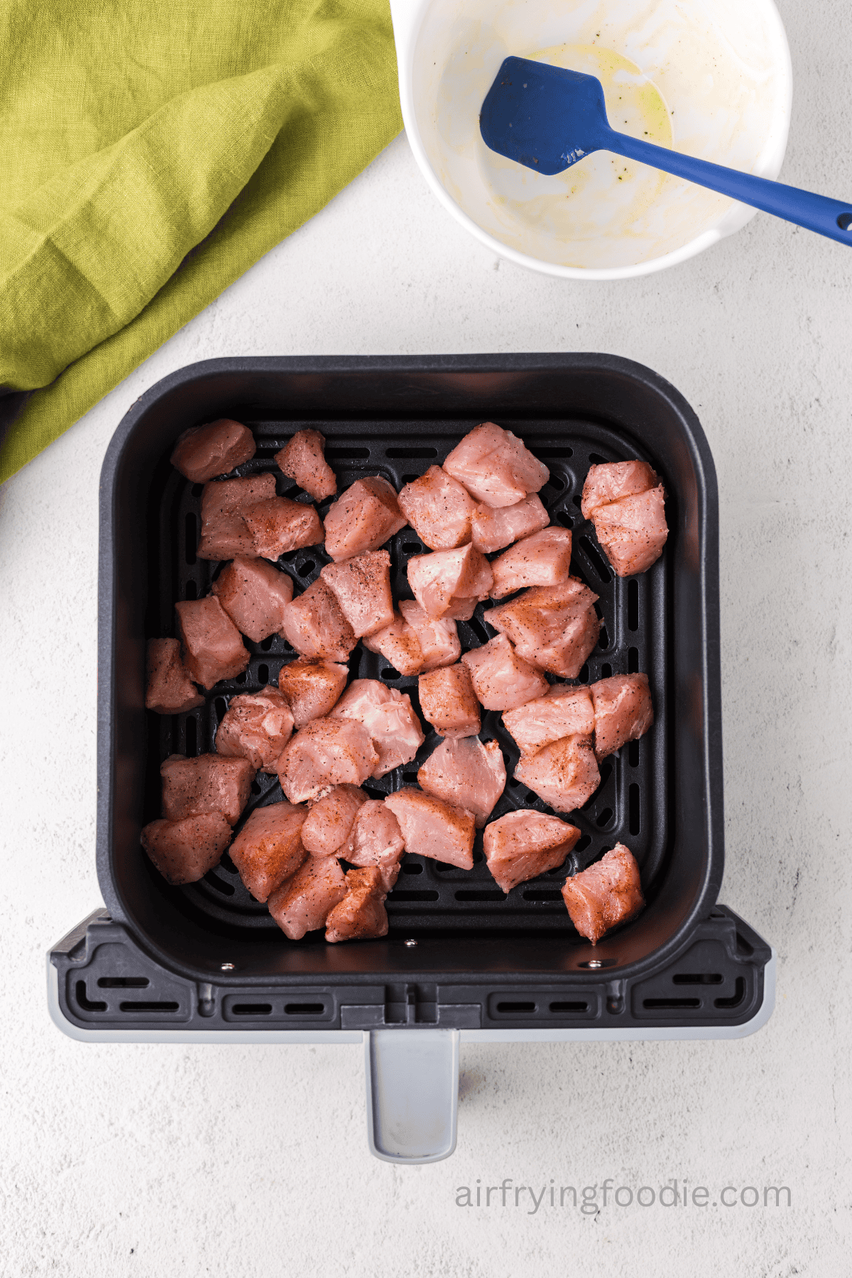 seasoned pork chop bites in the basket of the air fryer.