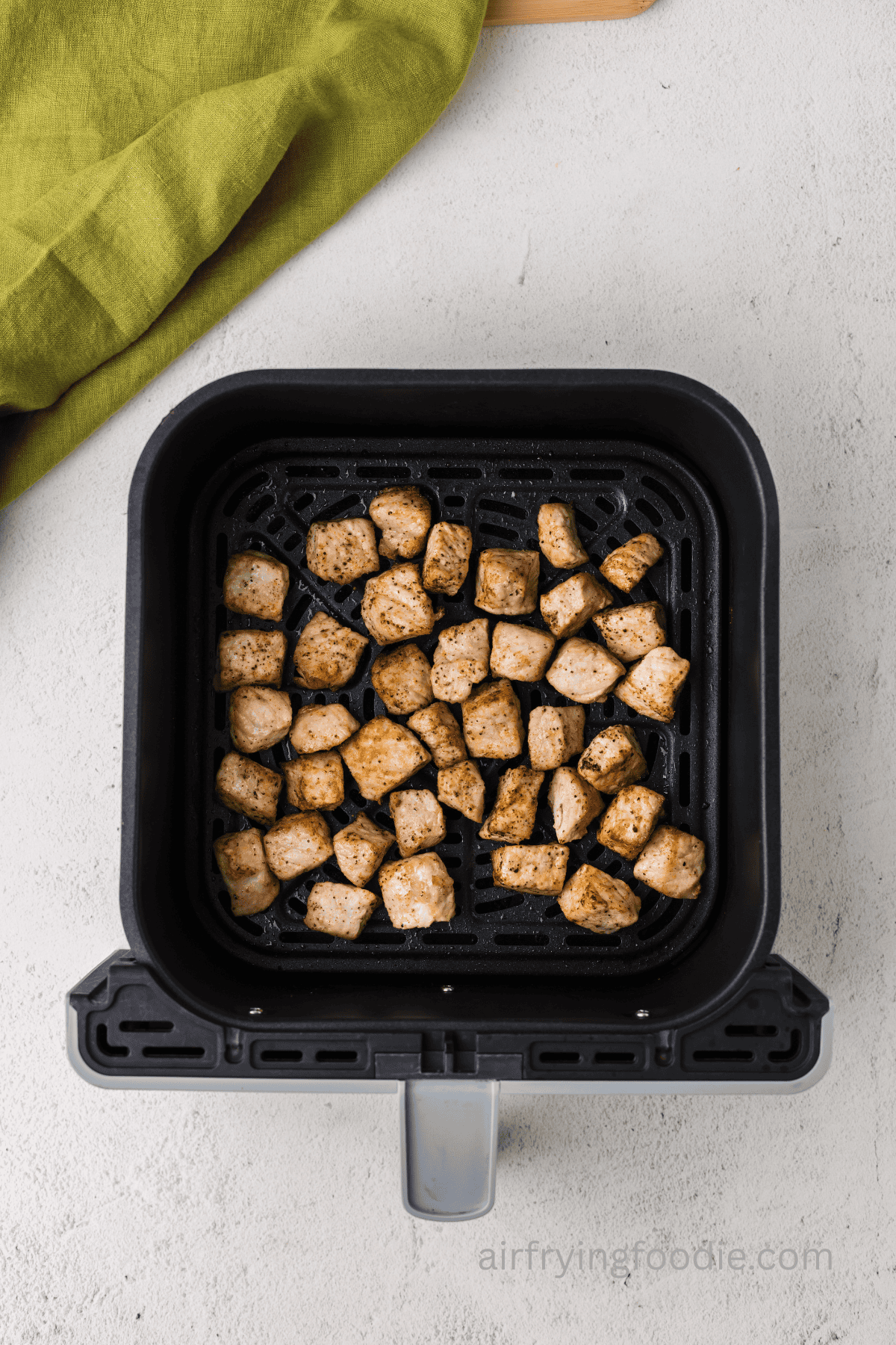 Cooked pork chop bites in the basket of the air fryer.