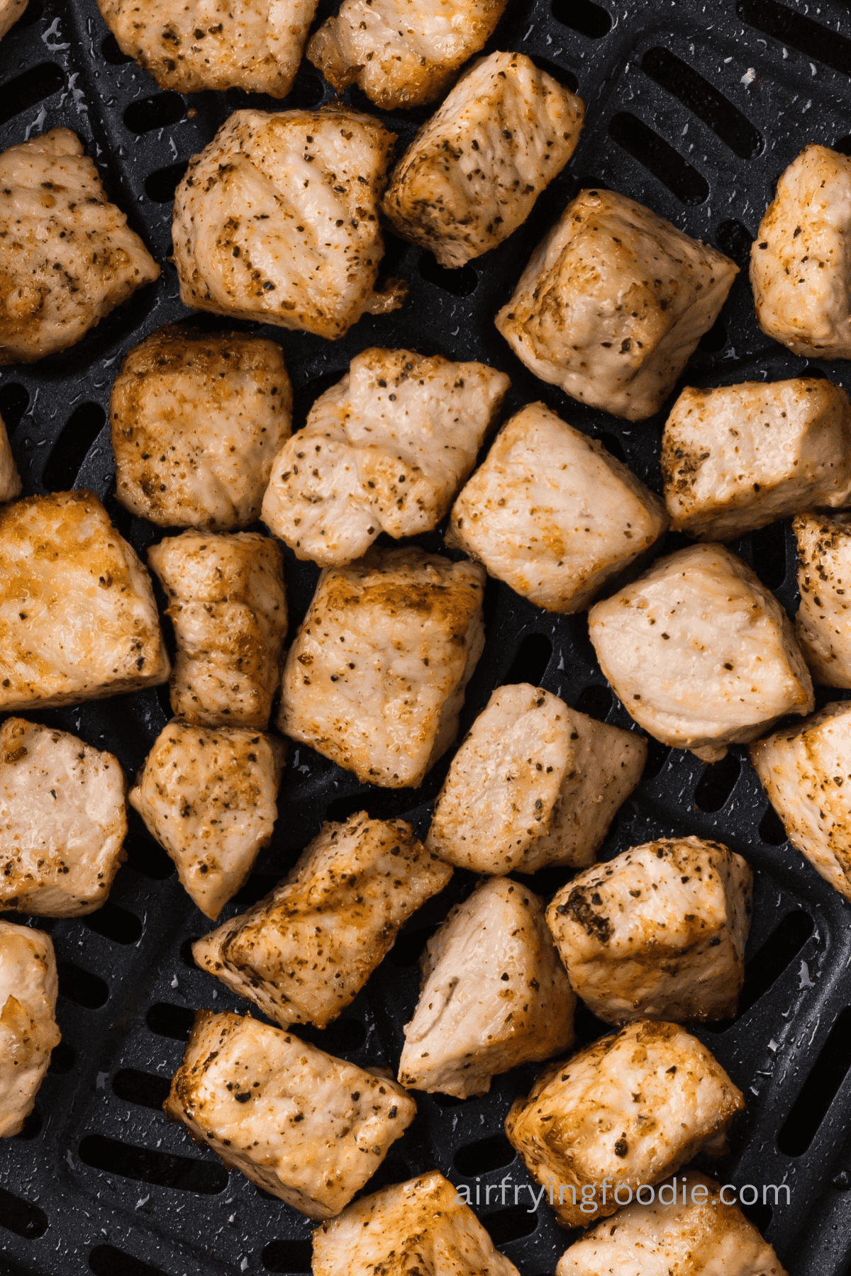 Close up of pork chop bites in the air fryer basket.