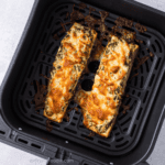 Close up of cheesy air fryre pesto salmon in the basket of the air fryer.