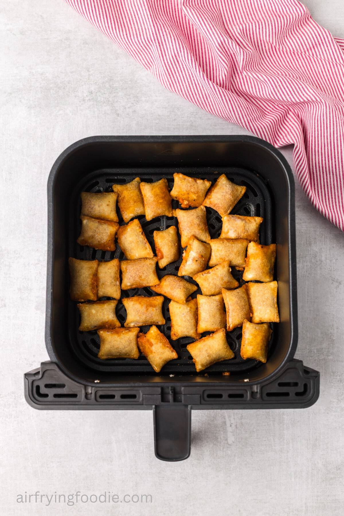 Cooked pizza rolls in an air fryer basket. 