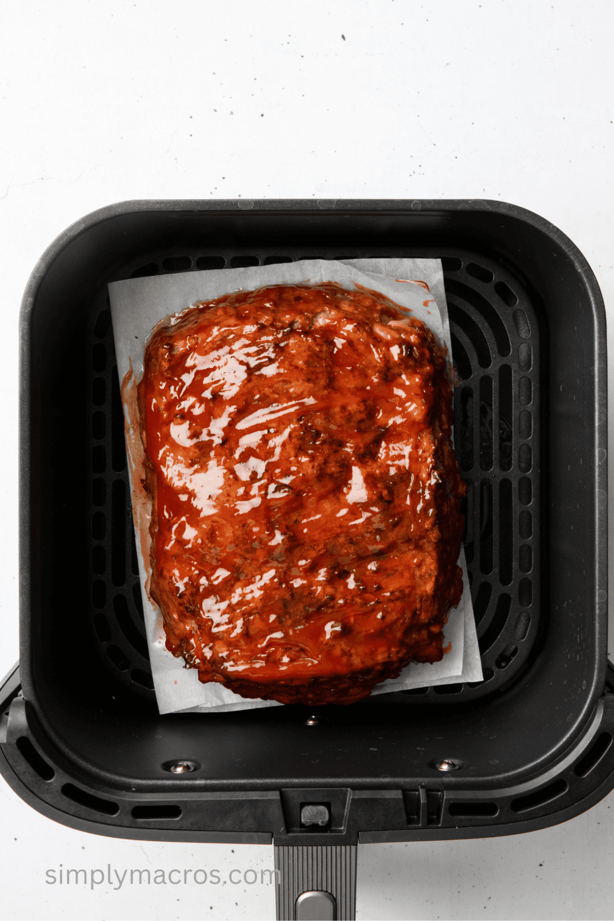 Turkey meatloaf in air fryer basket with glaze on top.