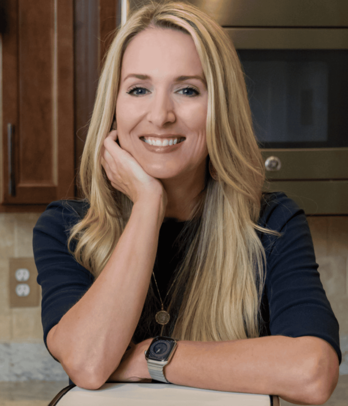 Picture of Jennifer in a kitchen resting on an air fryer.