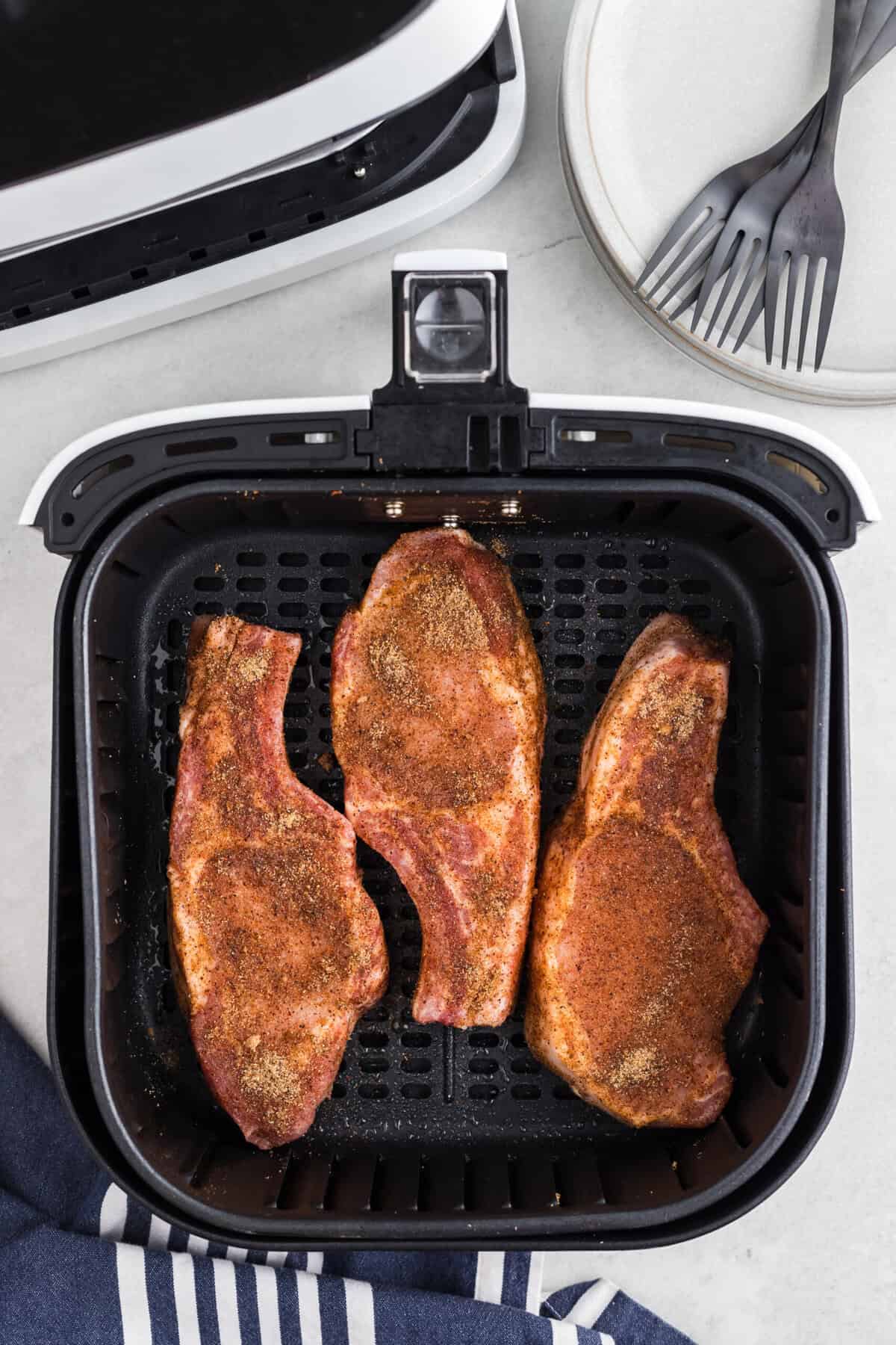 Pork steaks added to the air fryer basket.