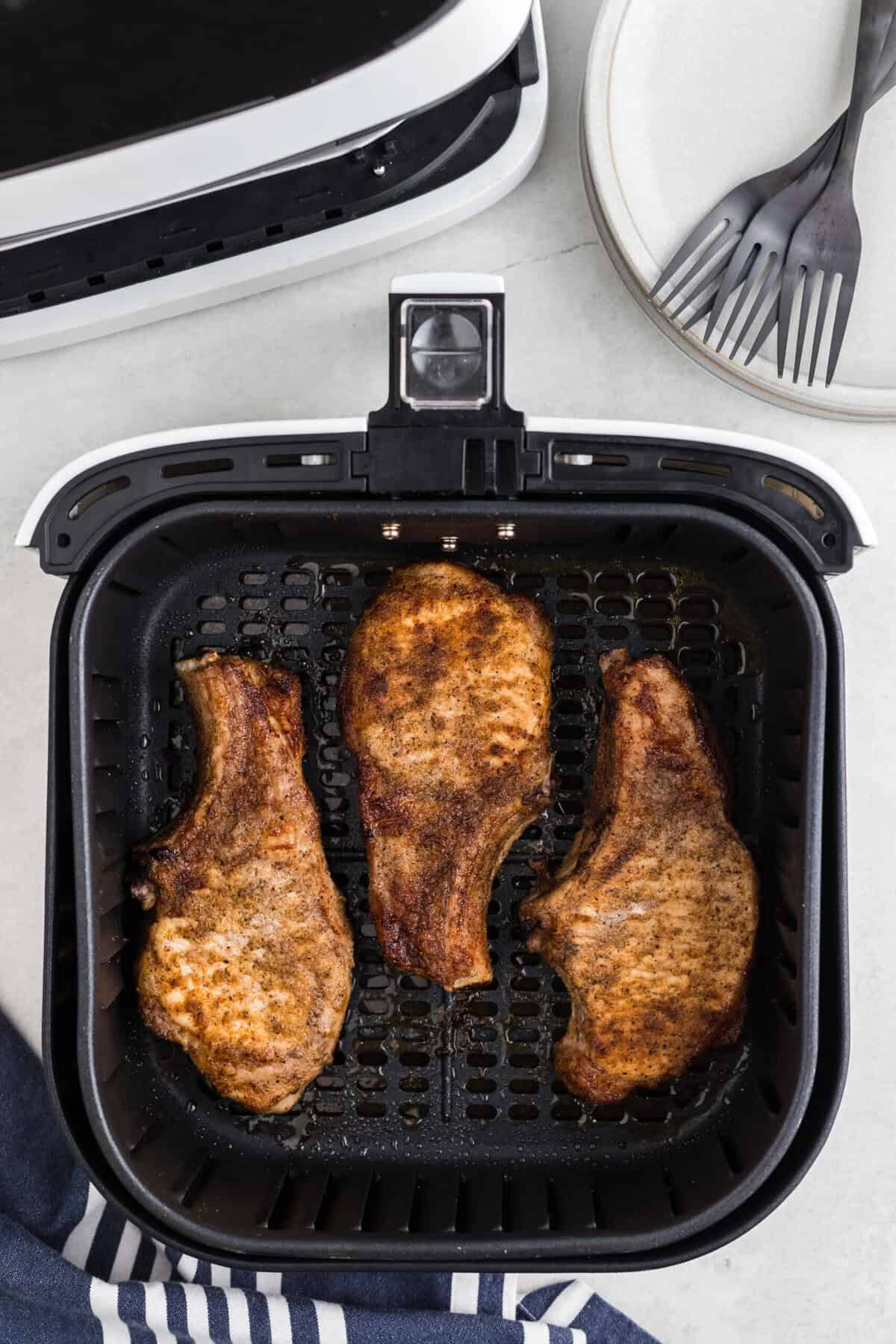 Air fryer pork steaks cooked in the air fryer basket.