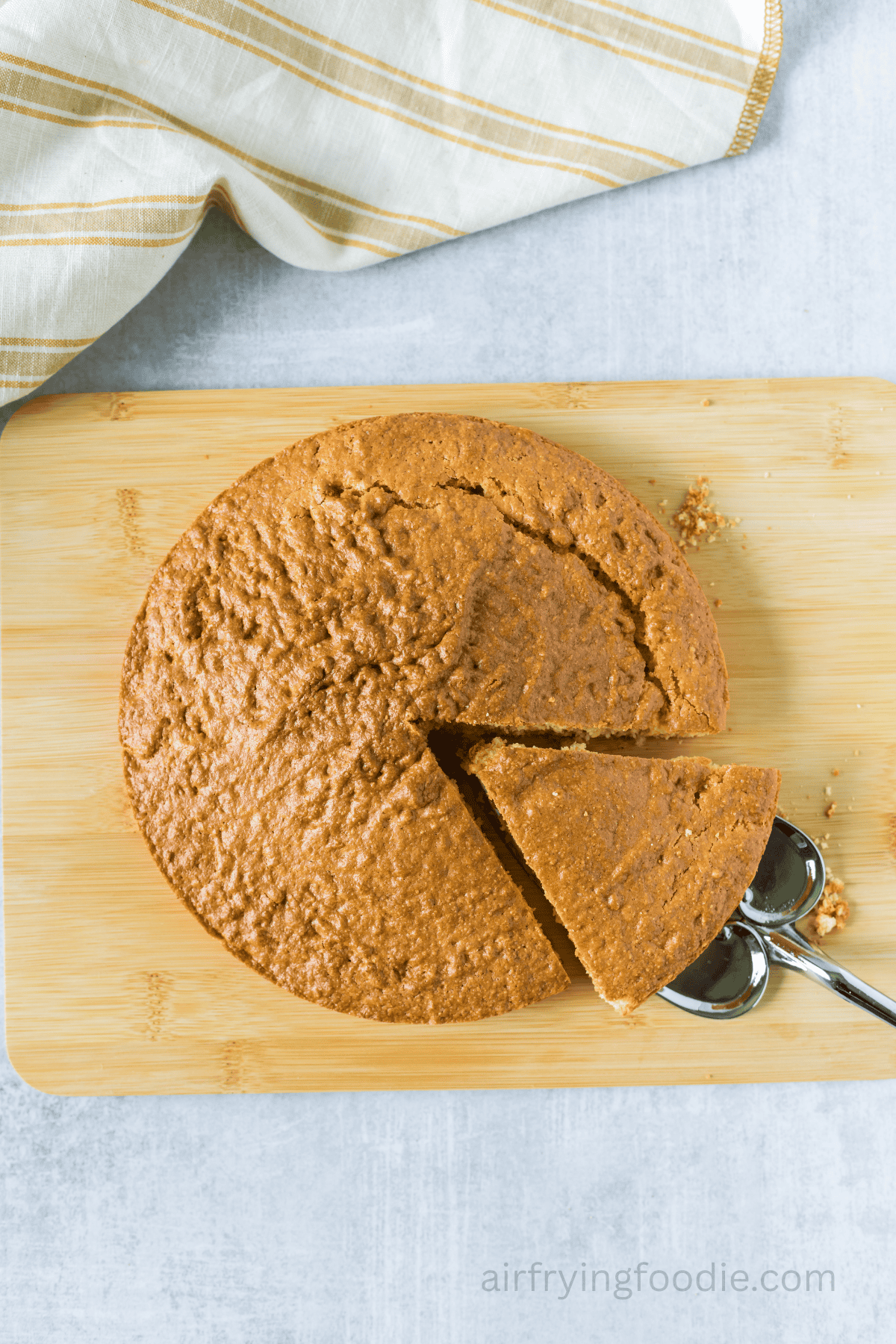Air-fried cornbread on a cutting board with a slice cut and a spatula pulling it out.