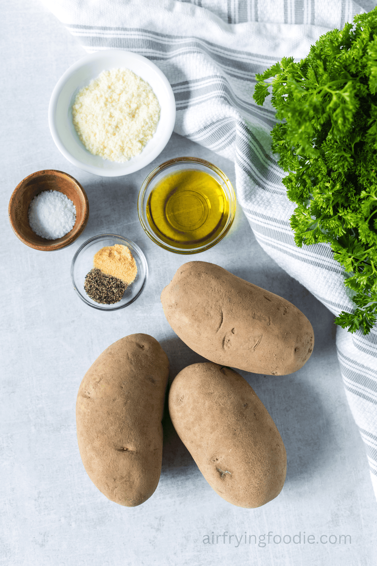Ingredients to make air fryer Hasselback potatoes on a white countertop.