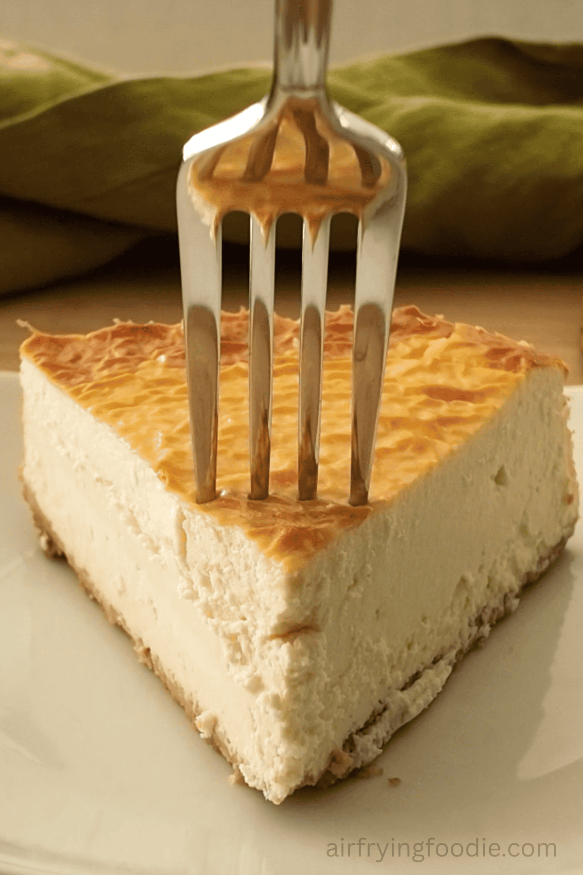 Close up of a slice of air fryer protein cheesecake with a fork about to take a bite.